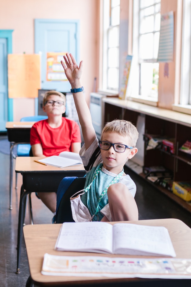 kindergarten classroom rules-kids raising his hand at desk