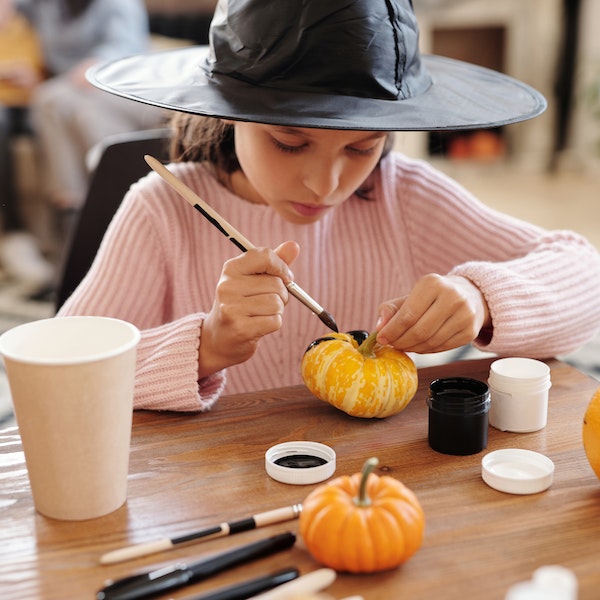 girl painting pumkin- classroom halloween party ideas